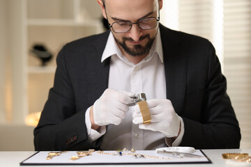 Appraiser with loupe evaluating luxury bracelet at table indoors