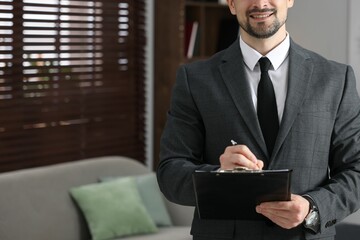 Professional psychologist with clipboard in his office, closeup. Space for text