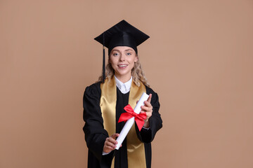 Happy student with diploma after graduation on beige background