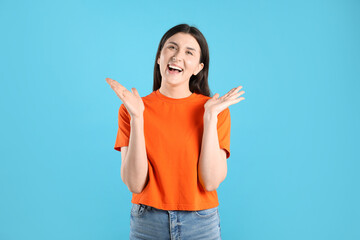 Portrait of surprised woman on light blue background