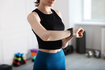 Woman checking fitness tracker during training indoors, closeup