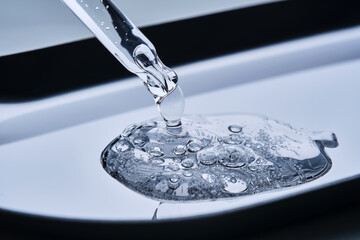 Hyaluronic serum drips from a pipette onto a steel tray.