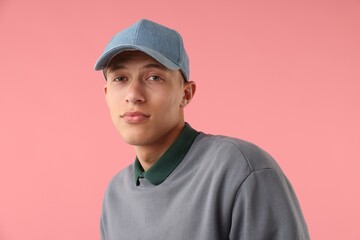 Young man in stylish baseball hat on pink background