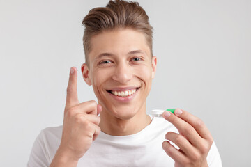 Man with contact lens and case on light background