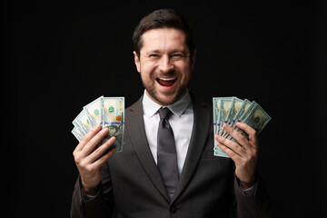 Happy greedy banker with dollar banknotes on black background