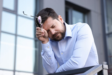 Tired businessman with glasses outside office building