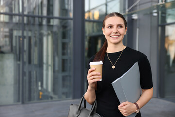 Successful businesswoman with coffee and folder near office building. Space for text