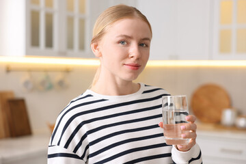Young woman with glass of water in kitchen