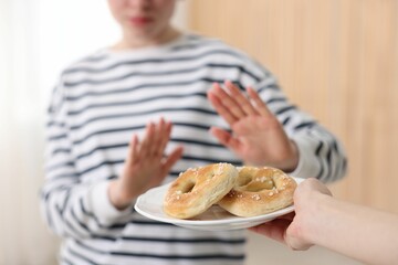 Gluten free diet. Woman refusing from pretzels indoors, selective focus