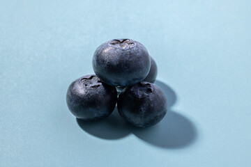 Three Blueberries Closeup on a Light Blue Background