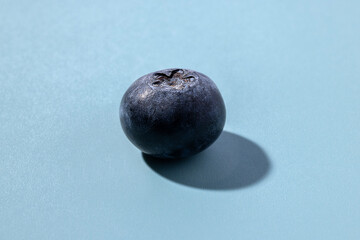 Closeup of a Single Blueberry on a Light Blue Background