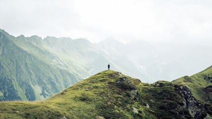Summer mountain landscape with a lone hiker atop a green hill at midday Generative AI