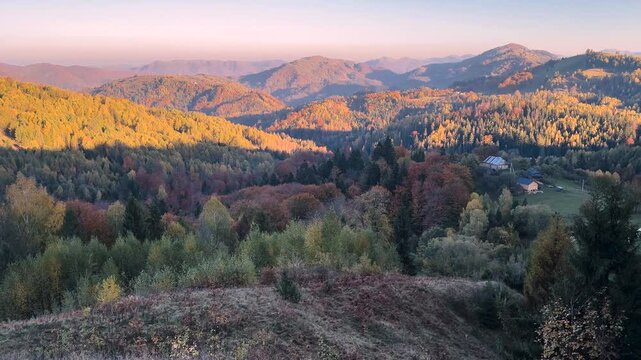 Ukraine, drone, flight in the Carpathians early in the autumn morning at sunrise near the city of Kosiv. Bright forests and dwellings of the Hutsul highlanders on the glades