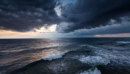 a dramatic stormy ocean under dark clouds illuminated by muted sunlight at dusk