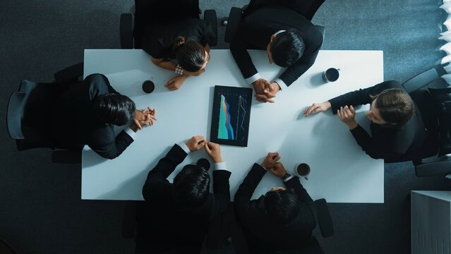 Time lapse of professional business team discuss and analyze data. Top down aerial of group of diverse people brainstorm marketing idea while looking at financial graph at meeting table. Directorate.