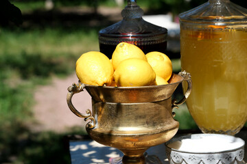 Bright lemons shine in a golden bowl beside refreshing drinks