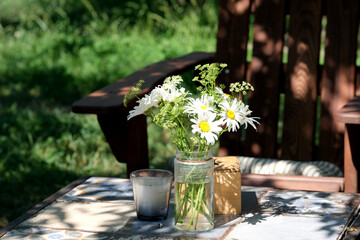 Sunlit garden table with blooming daisies and a cozy charm