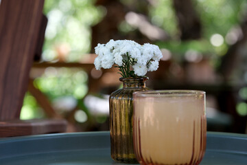 Refreshing drink and delicate flowers on a sunny day outdoors