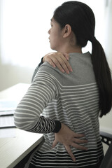 Tired asian business woman massaging rubbing stiff sore neck and back tensed muscles fatigued from...