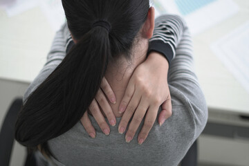 Tired asian business woman massaging rubbing stiff sore neck and back tensed muscles fatigued from...