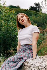 Young woman sitting outdoors near wall
