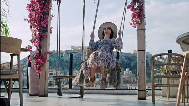 Happy woman enjoying a swing with a scenic Acropolis view in Athens, Greece, slow motion