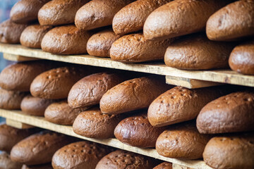 Freshly Baked Bread Loaves on Wooden Racks in Bakery