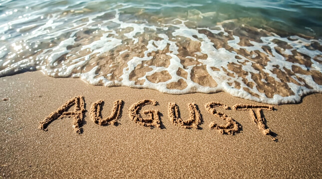 The month of August is etched into the sandy shore as a gentle wave with white foam recedes leaving sparkling water behind