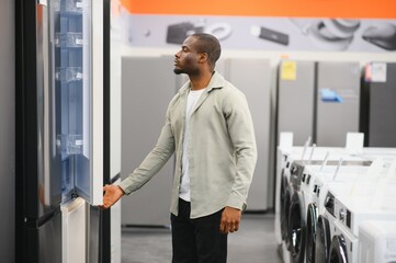Customer opening refrigerator door in electronics store appliance section