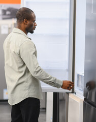Customer choosing refrigerator in electronics store appliance retail shop