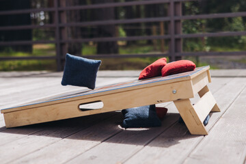 Cornhole game set, process of throwing bean bags, female girl tossing bean sacks, corn hole in the...