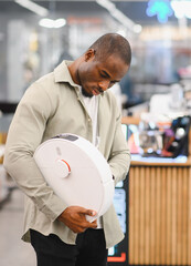 Customer choosing robotic vacuum cleaner in electronics store