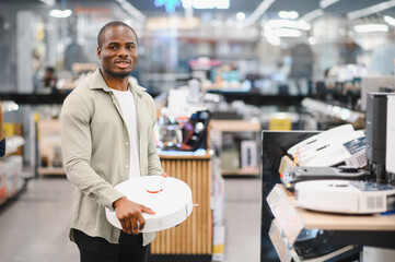 Customer holding robot vacuum cleaner in electronics store