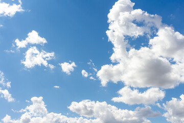 Bright clouds drift across a clear blue sky during midday