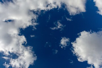 Bright clouds drift across a clear blue sky during midday