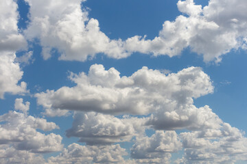 Bright clouds drift across a clear blue sky during midday
