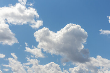Bright clouds drift across a clear blue sky during midday