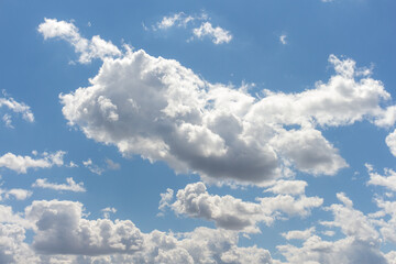 Bright clouds drift across a clear blue sky during midday