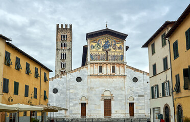 The stone facade of a historic church and bell tower in Lucca
