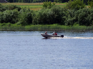Obraz premium Small Motorboat with Two People Cruising on a Wide River. Summer Activity.