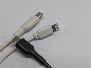 Close-up of three common charging cables: USB-C, Lightning, and Micro USB. Essential tech...