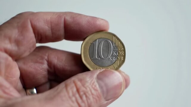 Hand holding a ten kroon coin