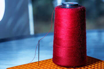 The red bobbin thread passing through the needle eye next to it
