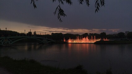 Sunset with colorful bright fountain over the river in the evening sky