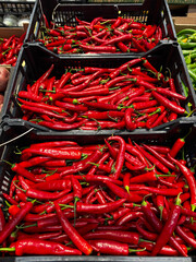 Crates full of hot peppers are displayed at a local market. A vibrant and spicy composition,...