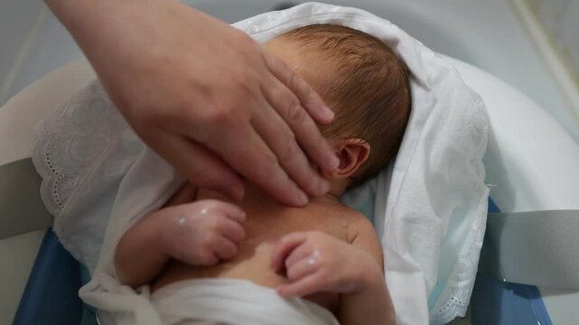 Newborn baby being gently bathed with farther wet hand