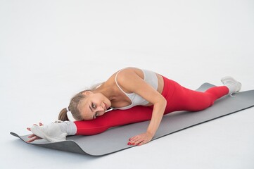 Young woman doing splits exercises on white background.