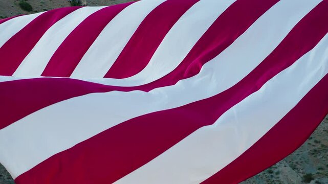 Epic drone close up on massive American flag flowing in rocky mountain canyon
