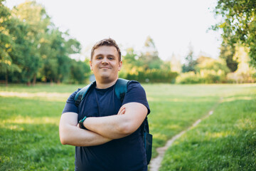 Happy 30s blonde man with backpack standing in the countryside. Traveler. Summer time. Positive...