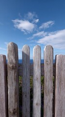 Rustic wooden fence against blue sky with ocean view